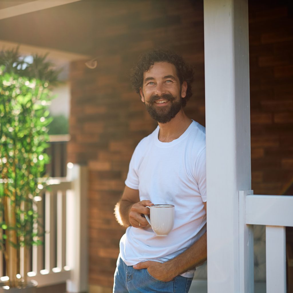smiling man enjoying morning coffee on porch 2026 01 09 12 00 46 utc